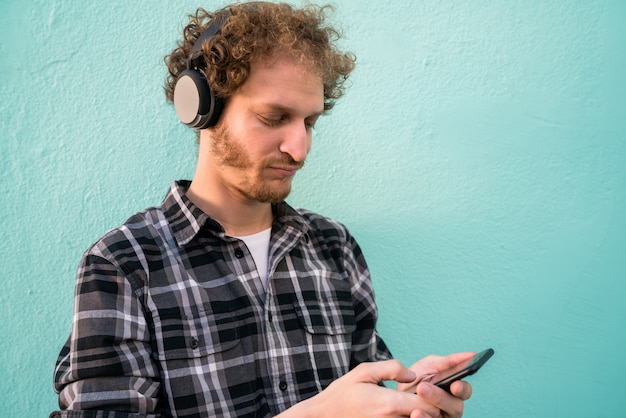 Homem ouvindo música com fones de ouvido e telefone móvel.