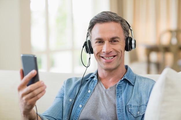 Homem ouvindo música em fones de ouvido na sala de estar em casa