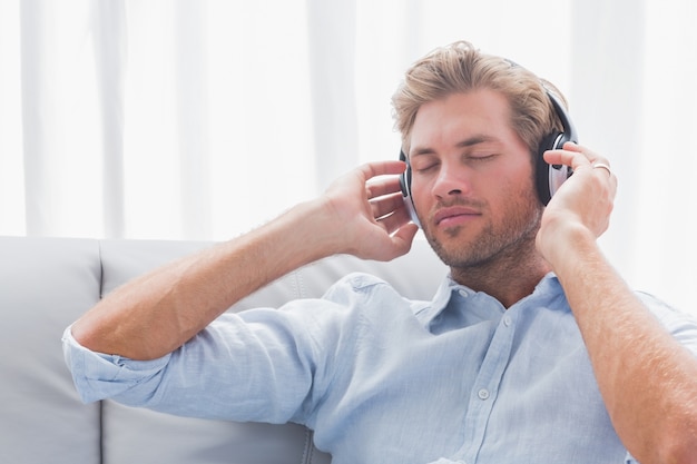 Homem ouvindo música em um sofá