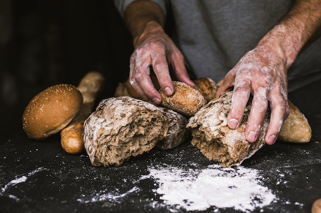 Homem padeiro segurando um pão rústico e orgânico nas mãos