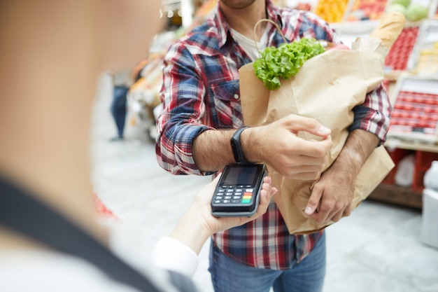 Homem pagando por Smartwatch no supermercado