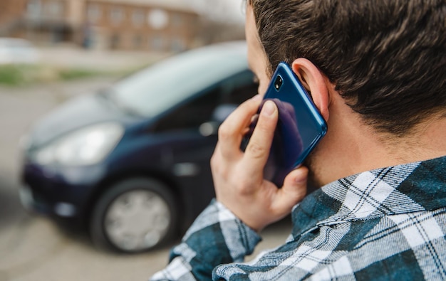 Homem parado ao lado do carro falando smartphone