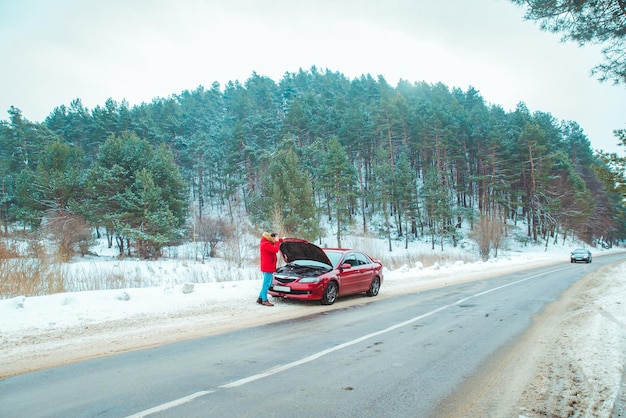 Homem parado perto de carro quebrado no clima de inverno nevado na estrada