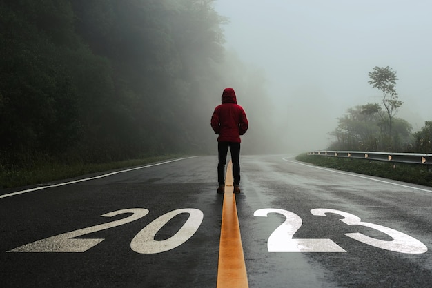 Foto homem parado sozinho na estrada e olhando para o alvo com o texto 2023 escrito na estrada.