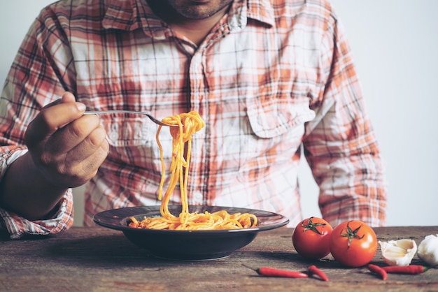 Foto homem, passe segurar, macarronada, garfo, prato, ligado, a, tabela madeira, em, restaurante, foco seletivo