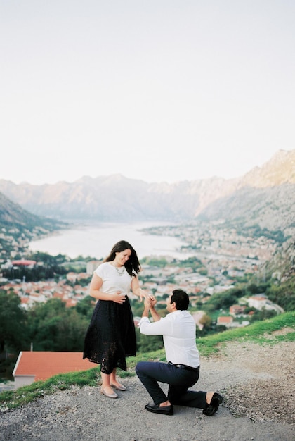 Homem pede mulher em casamento de joelhos em uma montanha com vista para a Baía de Kotor