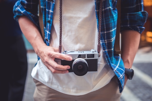 Foto homem pendurado câmera de filme no pescoço na rua andando e conceitos de viagens