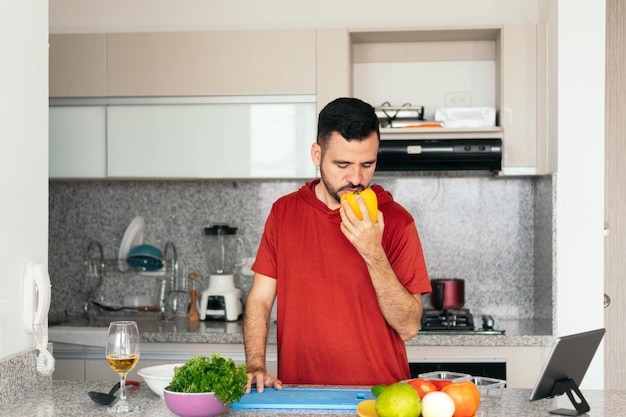 Homem pensativo cheirando vegetal na cozinha de sua casa