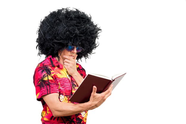 Foto homem pensativo em peruca afro e óculos de sol esfregando o queixo e lendo um livro interessante contra fundo branco