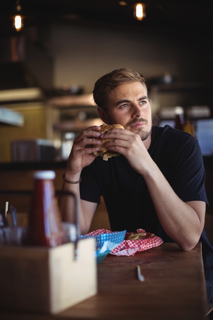 Foto homem pensativo segurando hambúrguer