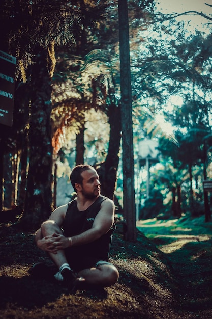 Foto homem pensativo sentado em terra na floresta