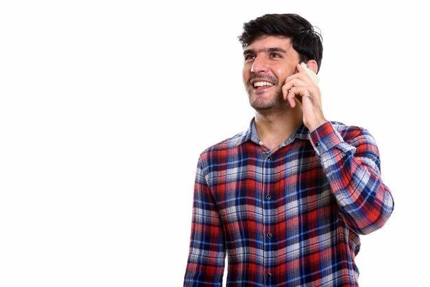 Foto homem persa jovem pensativo e feliz sorrindo enquanto fala no celular