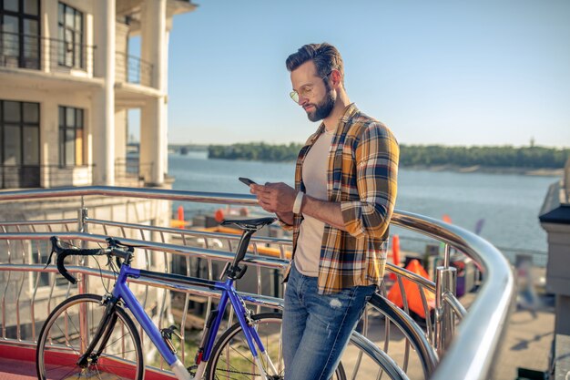 Homem perto de uma bicicleta com smartphone nas mãos