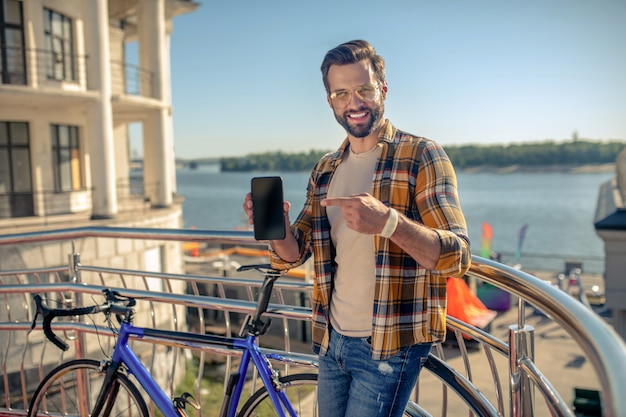 Homem perto de uma bicicleta com smartphone nas mãos