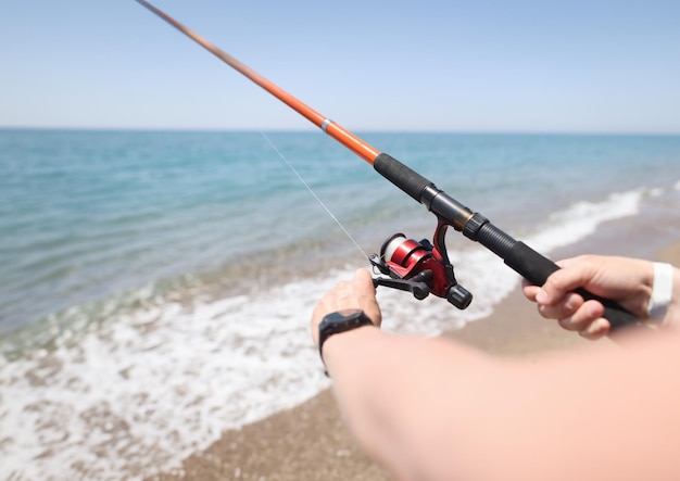 Homem pescando com vara na beira-mar