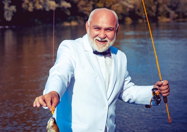 Homem pescando no lago com peixes Férias de verão Homem barbudo maduro aposentado de terno Brutal m