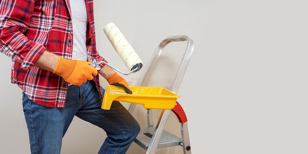 Homem pintando a parede da bandeira horizontal do conceito diy em casa com lugar para texto