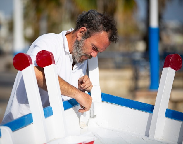 homem pintando barco a remo tradicional com pincel