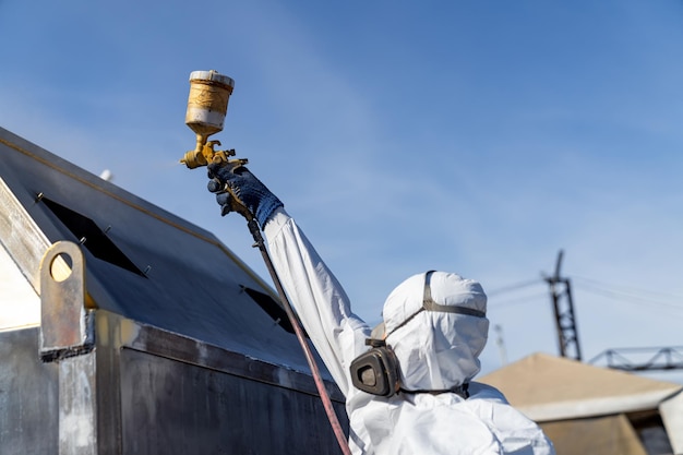 Homem pintando em traje especial Reparando o spray vestindo traje e equipamento de proteção