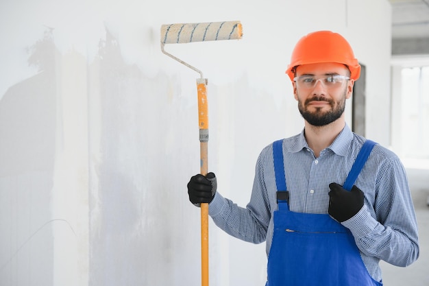 Homem pintor pintando a parede com rolo de pintura