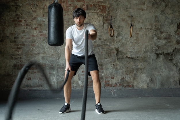 Homem poderoso treinando com corda em treinamento funcional fitness ginásio crossfit cordas exercício durante o treinamento de atleta na academia de ginástica