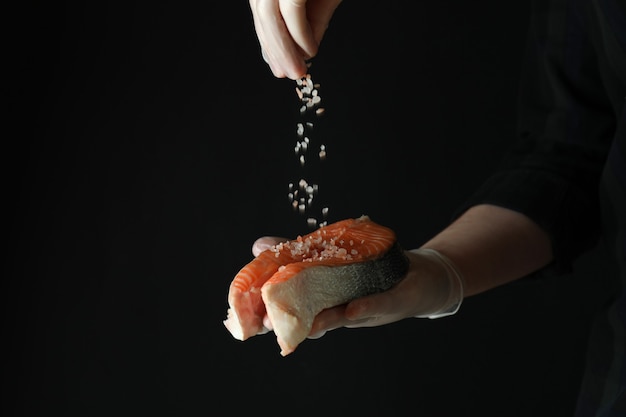 Foto homem polvilhe sal na carne de salmão no escuro