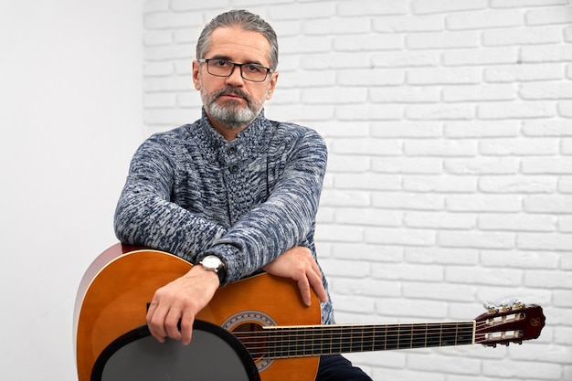 Homem posando com guitarra no estúdio.