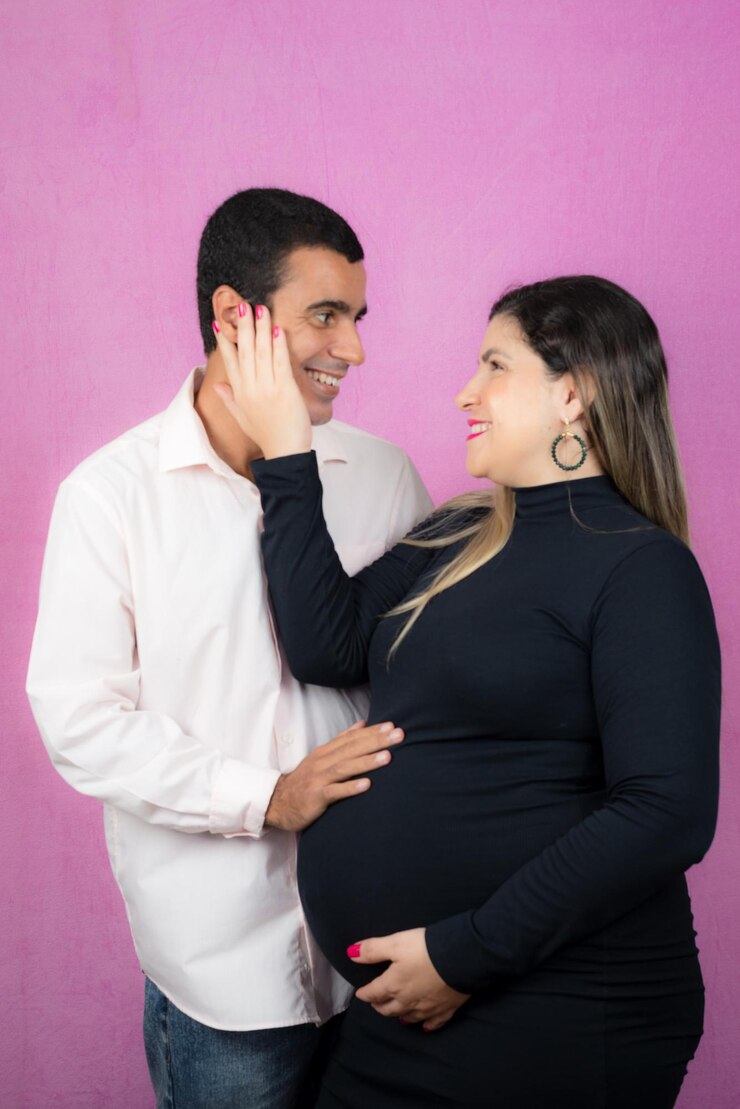 Foto homem posando com sua esposa grávida isolada em fundo rosa
