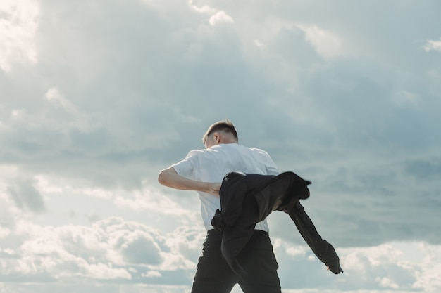 Homem posando para a câmera na frente do céu nublado.