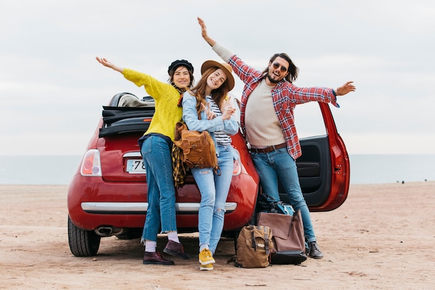 Foto homem positivo, com, mãos erguidas, perto, abraçar, mulheres, e, car, ligado, praia mar