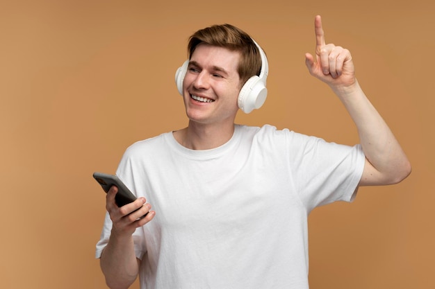 Homem positivo ouvindo música ou rádio em smartphone usando fone de ouvido e dançando