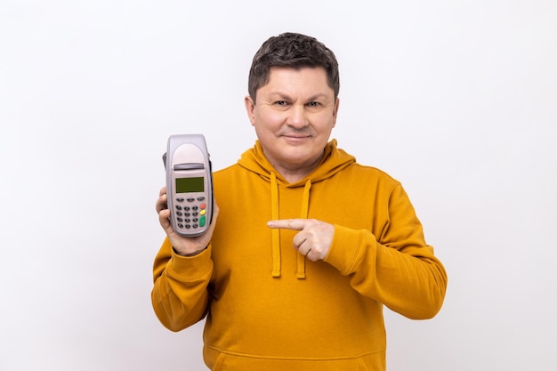 Homem positivo sorridente segurando apontando para o terminal de pagamento pos usando paypass para pagamento de compras