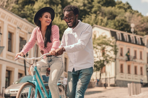 Homem positivo sorrindo e senhora feliz andando de bicicleta