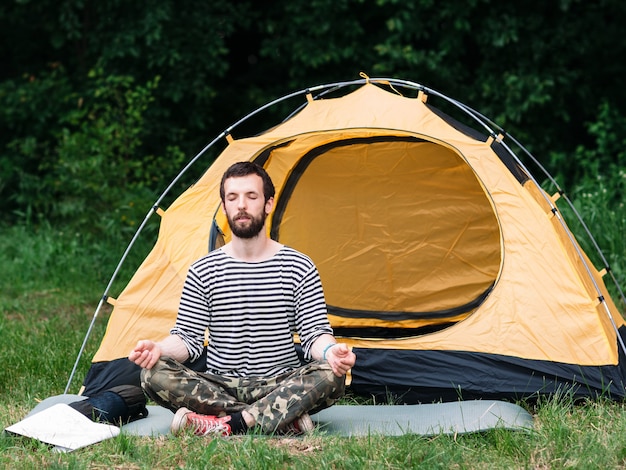 Homem praticando ioga em acampamento