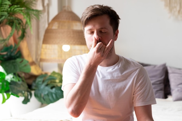 homem praticando ioga sentado fazendo exercício de respiração de narina alternativa nadi shodhana pranayama