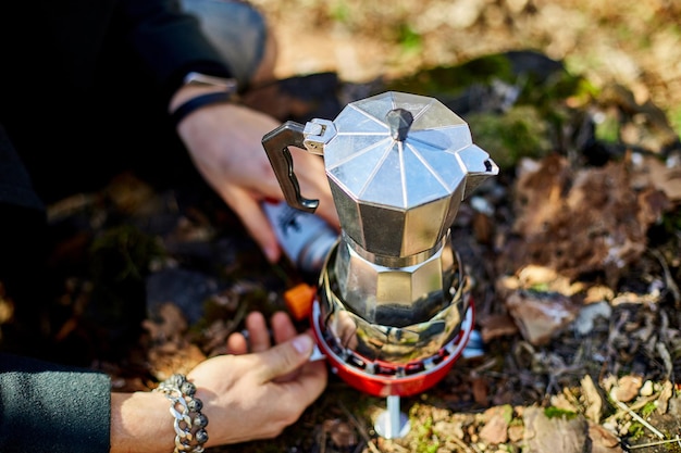 Homem preparando café de uma cafeteira gêiser em um queimador de gás