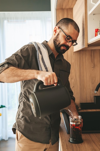 Homem preparando chá preto em um bule