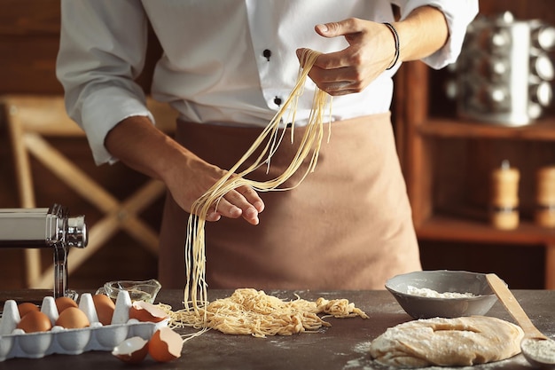 Foto homem preparando macarrão na mesa da cozinha vista de perto