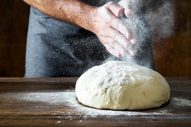 Homem preparando massa de pão na mesa de madeira em padaria