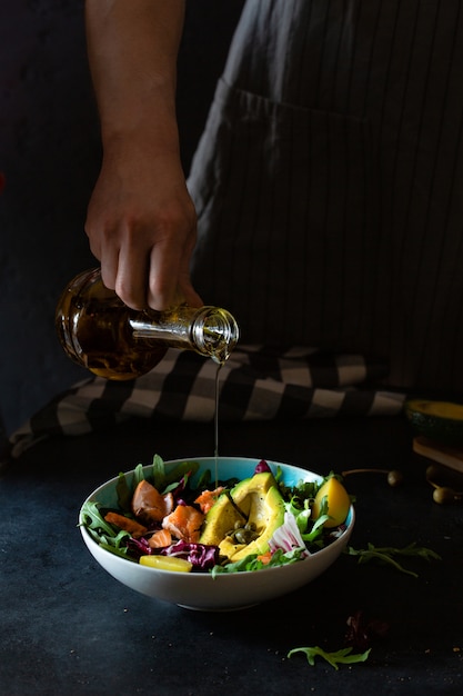 Homem preparando salada de salmão grelhado com abacate