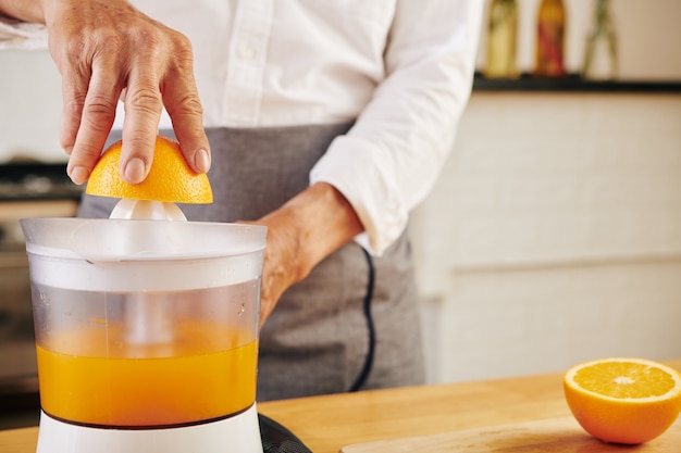 Homem preparando suco de laranja