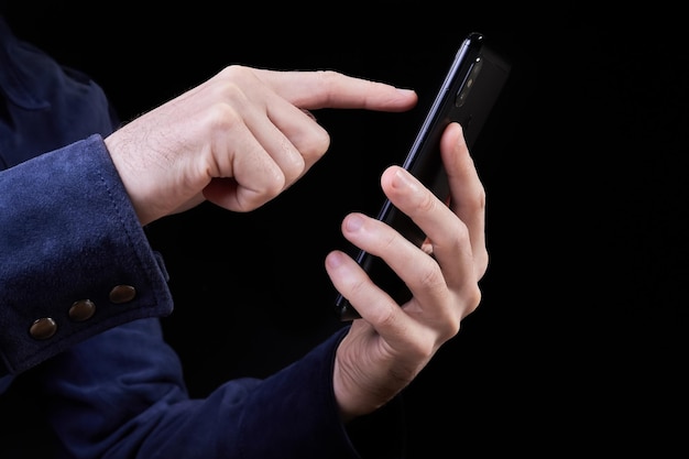 Homem pressiona o dedo na tela de um smartphone em um fundo escuro