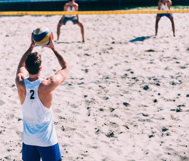 Foto homem prestes a sacar a bola durante jogo de vôlei de praia