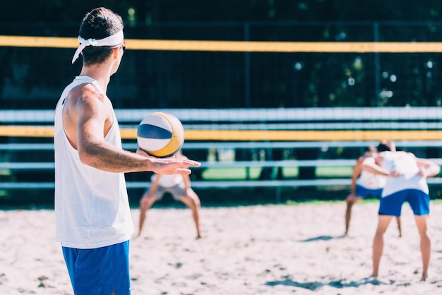 Homem prestes a sacar a bola durante jogo de vôlei de praia