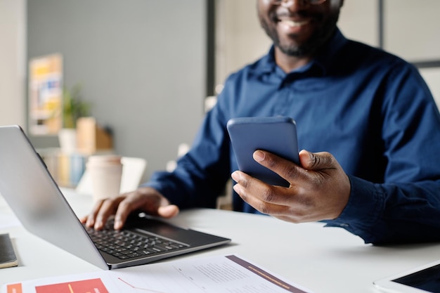 Homem preto a verificar mensagens no smartphone.