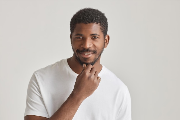 Homem preto bonito sorrindo para a câmera contra o branco