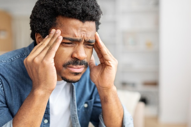 Homem preto estressado com dor de cabeça severa em casa