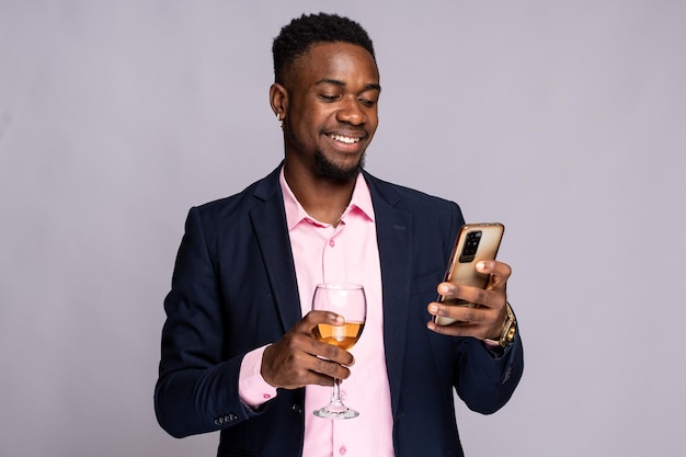 homem preto usando seu telefone, segurando um copo de vinho