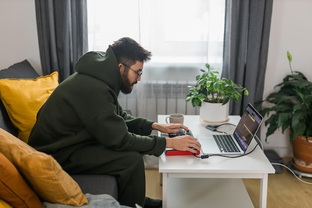 Homem produtor musical ou arranjador usando laptop e teclado midi e outros equipamentos de áudio para criar música em estúdio doméstico Beat fazendo e organizando conteúdo de áudio e compondo o conceito de música