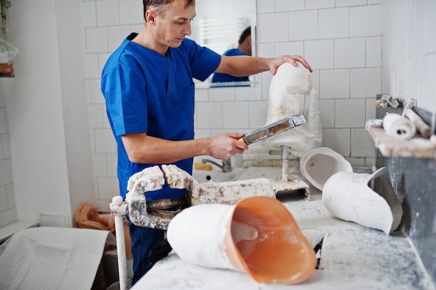 Homem protético fazendo perna protética enquanto trabalhava em laboratório, faz um modelo de gesso.